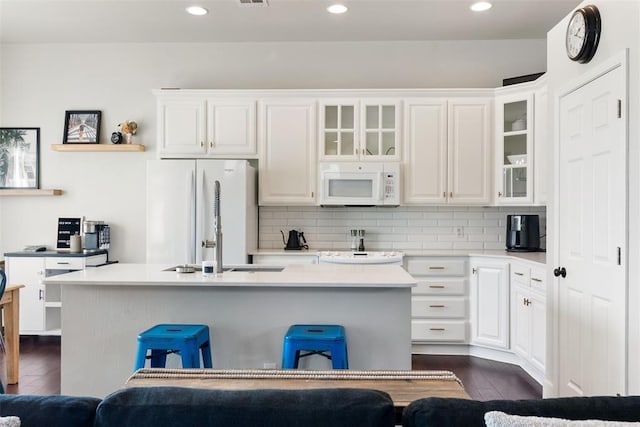 kitchen with white cabinetry, white appliances, an island with sink, and tasteful backsplash