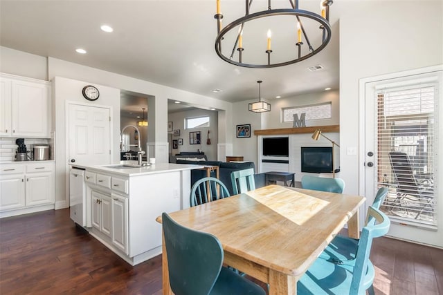 dining space with sink, dark hardwood / wood-style floors, and an inviting chandelier