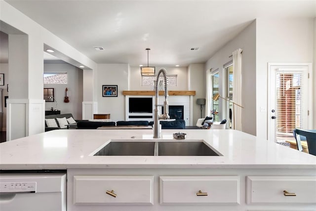 kitchen with light stone countertops, white dishwasher, white cabinets, and sink