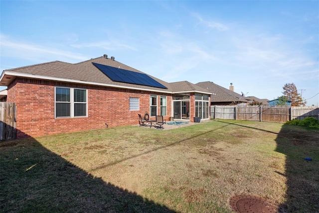 back of house featuring solar panels, a yard, a patio area, and a sunroom