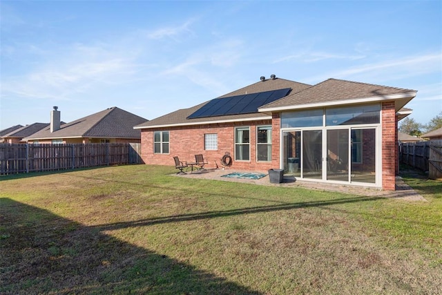 back of house with solar panels, a patio, a sunroom, and a lawn