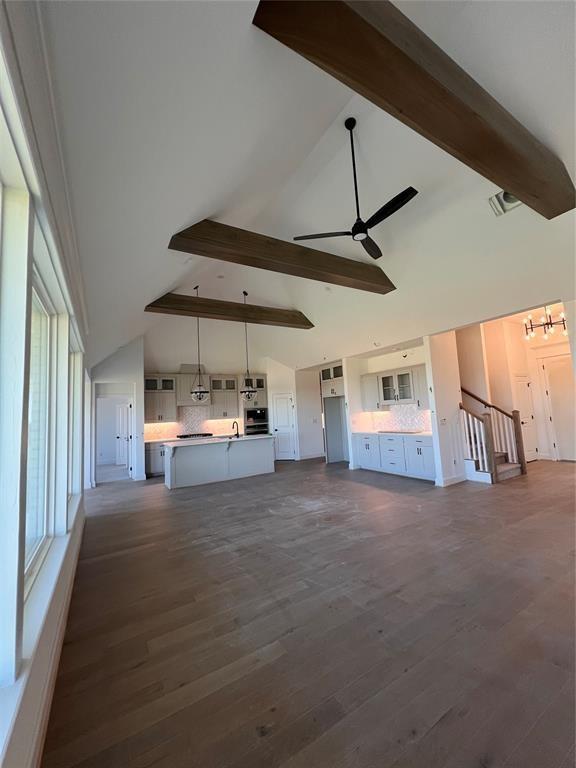 unfurnished living room with beam ceiling, ceiling fan, sink, dark wood-type flooring, and high vaulted ceiling