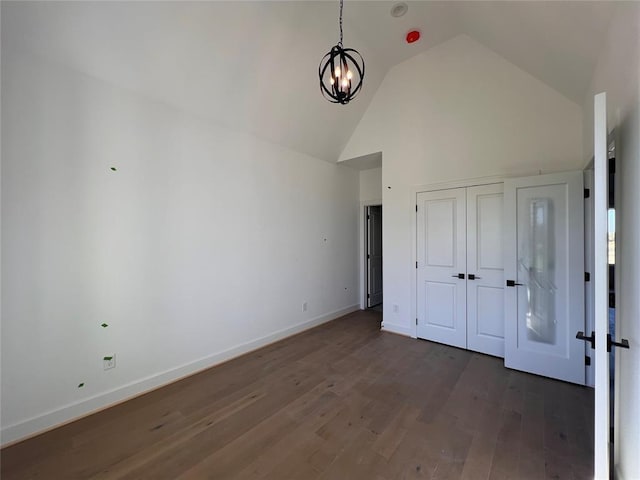 unfurnished bedroom featuring dark hardwood / wood-style flooring, high vaulted ceiling, and a notable chandelier