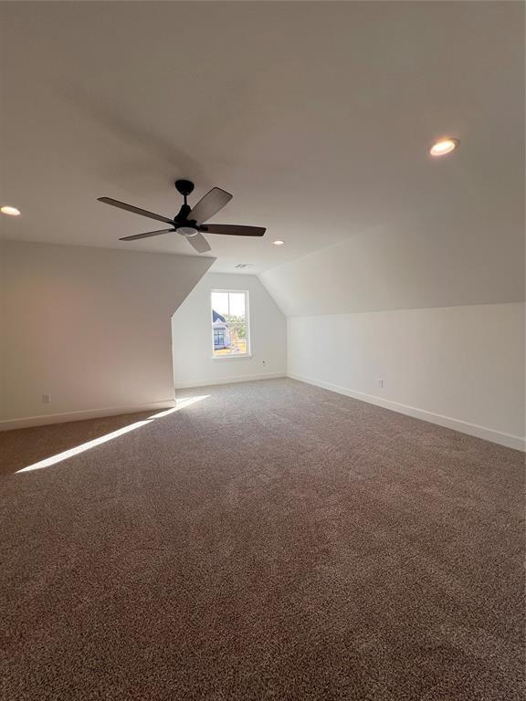 additional living space with ceiling fan, lofted ceiling, and dark colored carpet