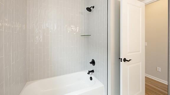 full bathroom with baseboards, shower / washtub combination, and wood finished floors