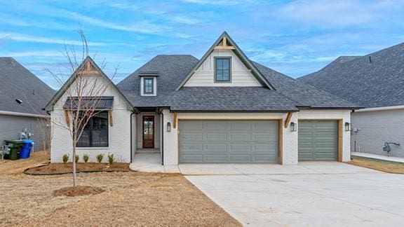 view of front facade with a garage, driveway, and a shingled roof