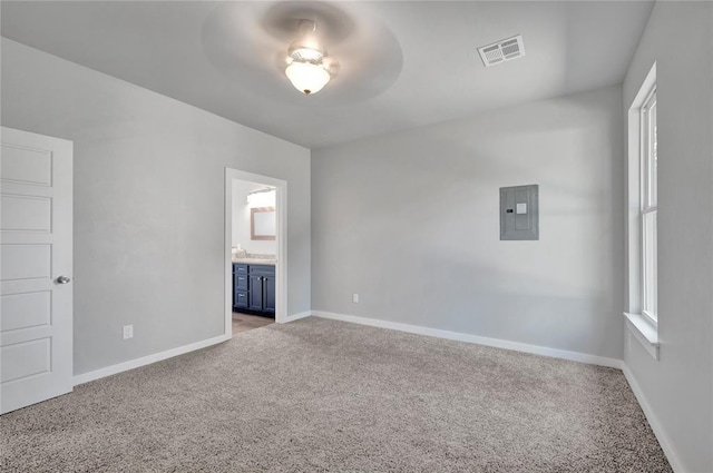 interior space with ensuite bath, ceiling fan, electric panel, and light carpet