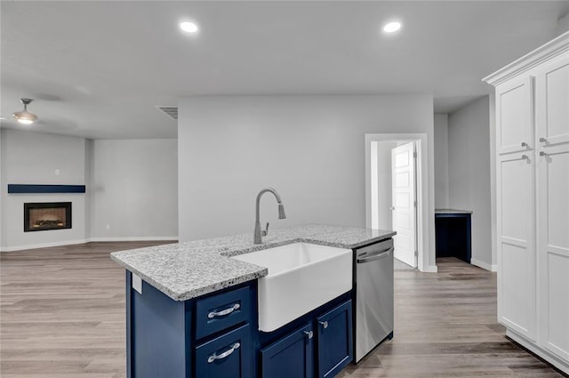 kitchen featuring white cabinetry, blue cabinets, stainless steel dishwasher, and sink