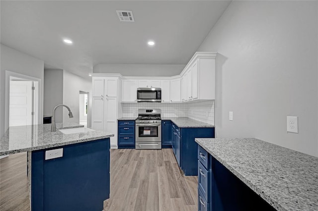 kitchen featuring sink, tasteful backsplash, blue cabinets, white cabinets, and appliances with stainless steel finishes