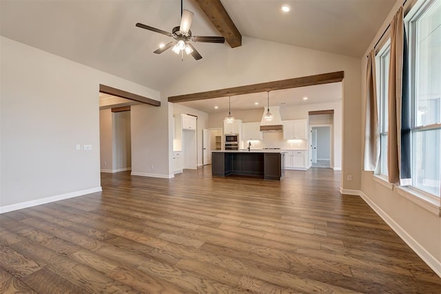 unfurnished living room with vaulted ceiling with beams, ceiling fan, dark hardwood / wood-style flooring, and sink