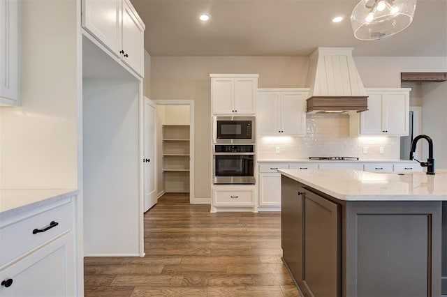 kitchen featuring custom range hood, black microwave, oven, decorative light fixtures, and white cabinetry