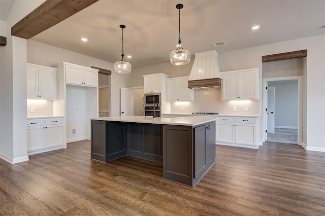 kitchen featuring white cabinets, a center island with sink, built in microwave, and dark hardwood / wood-style floors