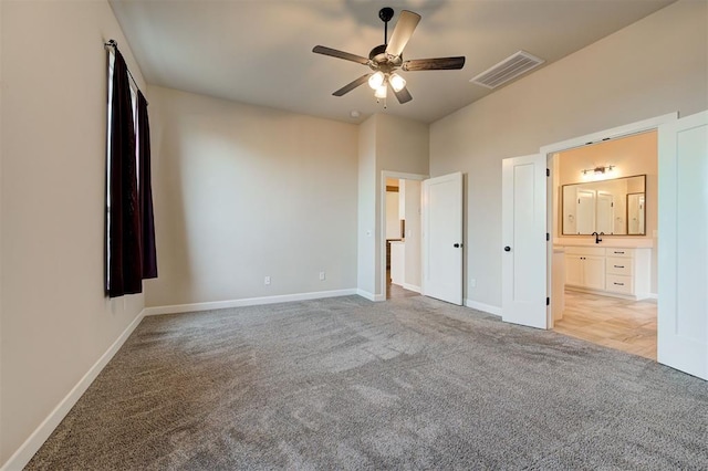 unfurnished bedroom featuring ceiling fan, light colored carpet, and ensuite bath