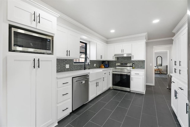 kitchen featuring sink, backsplash, white cabinets, dark tile patterned flooring, and appliances with stainless steel finishes