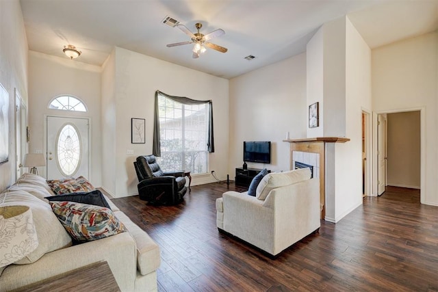 living room featuring a tiled fireplace, a wealth of natural light, dark hardwood / wood-style flooring, and ceiling fan