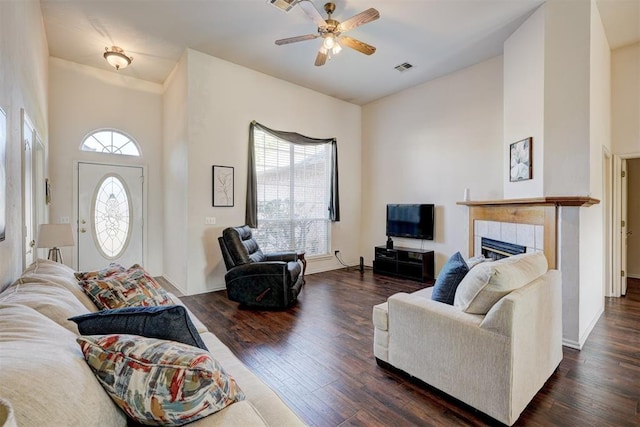 living room featuring dark hardwood / wood-style floors, ceiling fan, plenty of natural light, and a tile fireplace