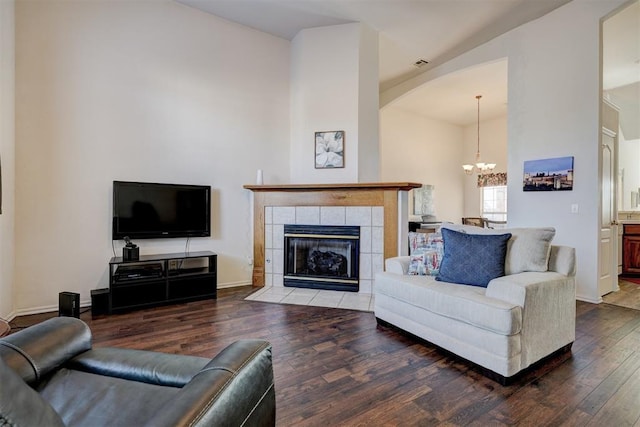 living room with a tile fireplace, wood-type flooring, and an inviting chandelier