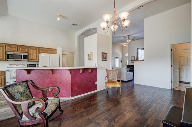 kitchen featuring dark hardwood / wood-style floors, white refrigerator with ice dispenser, stove, pendant lighting, and a kitchen bar