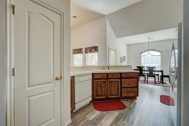 kitchen with pendant lighting, white dishwasher, sink, plenty of natural light, and light hardwood / wood-style floors