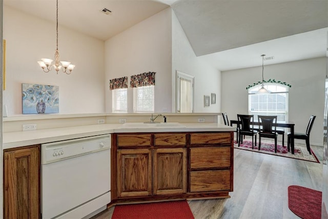 kitchen with dishwasher, sink, hanging light fixtures, light wood-type flooring, and a notable chandelier