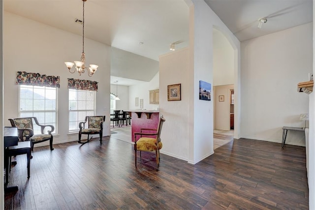 sitting room with dark hardwood / wood-style flooring, high vaulted ceiling, and an inviting chandelier