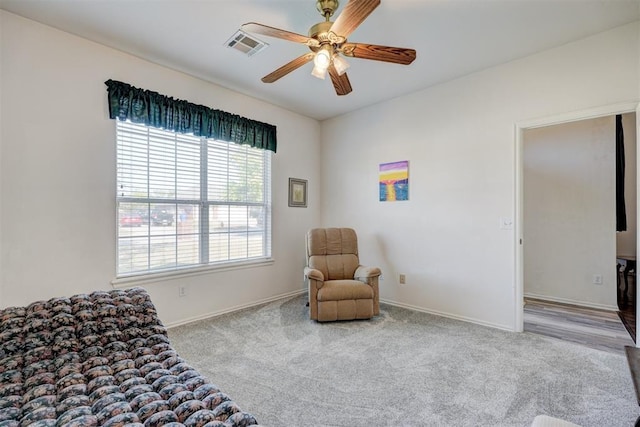 living area featuring light colored carpet and ceiling fan