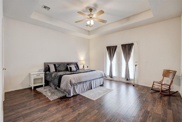 bedroom featuring ceiling fan, dark hardwood / wood-style flooring, and a tray ceiling