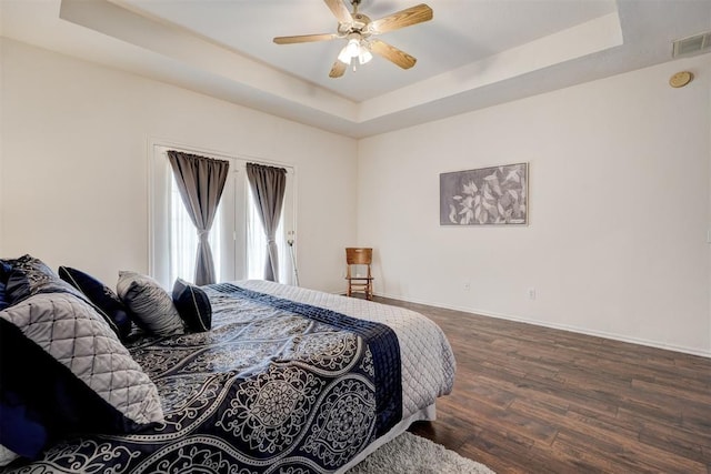 bedroom with dark hardwood / wood-style flooring, a raised ceiling, and ceiling fan