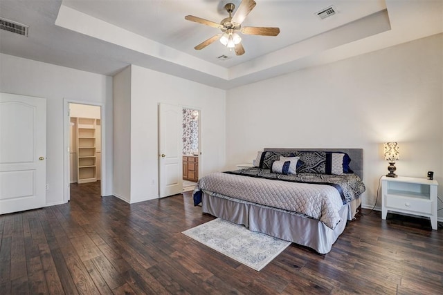 bedroom featuring a tray ceiling, a spacious closet, and ceiling fan