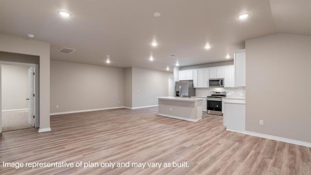 13581 Hickory Way, Edmond, OK 73025 - kitchen featuring appliances with stainless steel finishes, open floor plan, an island with sink, white cabinets, and light wood-style flooring