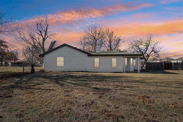 exterior space featuring a chimney, fence, a lawn, and brick siding