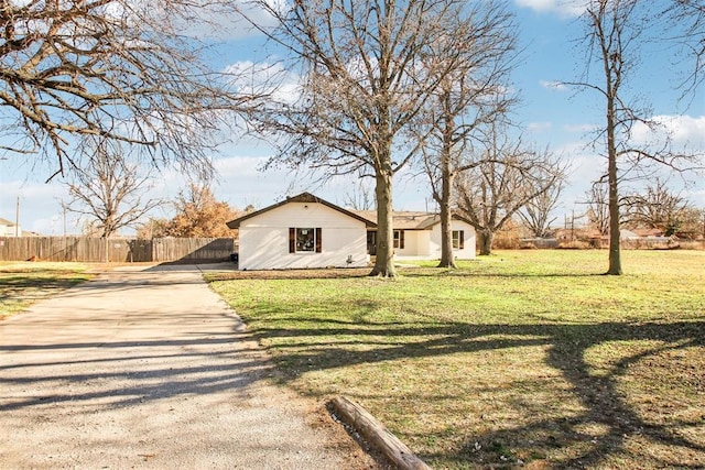 view of side of property featuring concrete driveway, fence, and a lawn