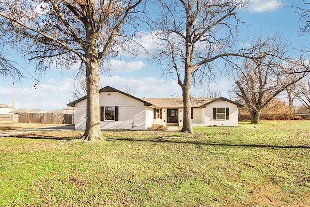 back of house featuring brick siding, a lawn, and fence