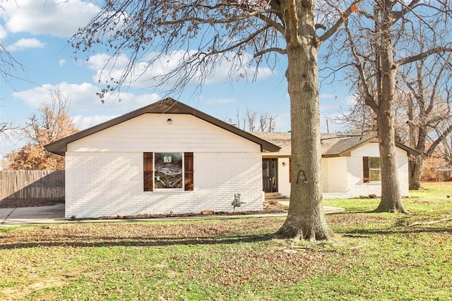 exterior space featuring a front yard, brick siding, and fence