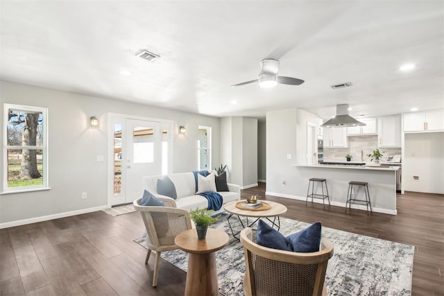 living area featuring dark wood-type flooring, visible vents, and baseboards