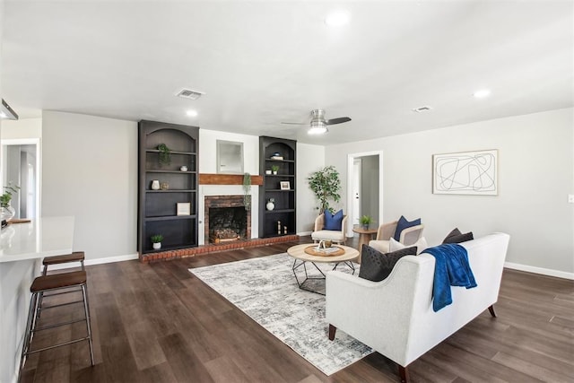 living room with dark wood-style flooring, visible vents, a fireplace, and baseboards