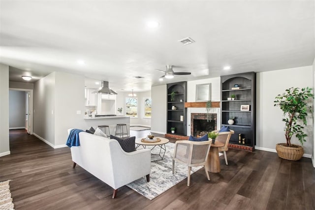 living area featuring a brick fireplace, baseboards, dark wood-style floors, and visible vents