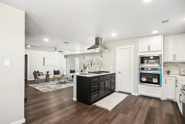 kitchen with decorative backsplash, dark wood-type flooring, range hood, light countertops, and white cabinetry