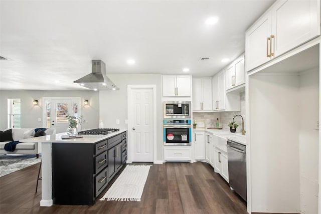 kitchen featuring stainless steel appliances, light countertops, white cabinets, and wall chimney exhaust hood