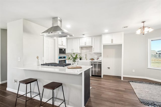 kitchen featuring visible vents, appliances with stainless steel finishes, a peninsula, extractor fan, and white cabinetry