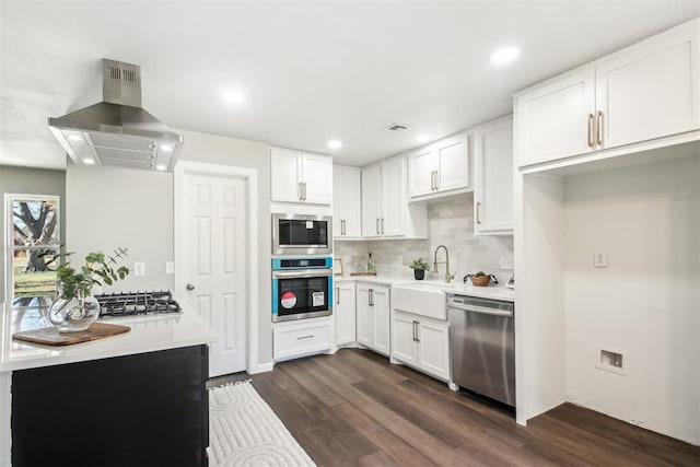 kitchen with white cabinetry, island exhaust hood, appliances with stainless steel finishes, and a sink