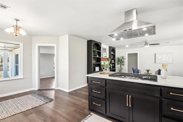 kitchen with dark wood-style flooring, visible vents, light countertops, wall chimney range hood, and stainless steel gas stovetop