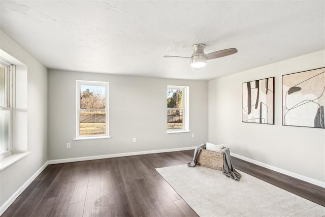 unfurnished room featuring ceiling fan, wood finished floors, and baseboards