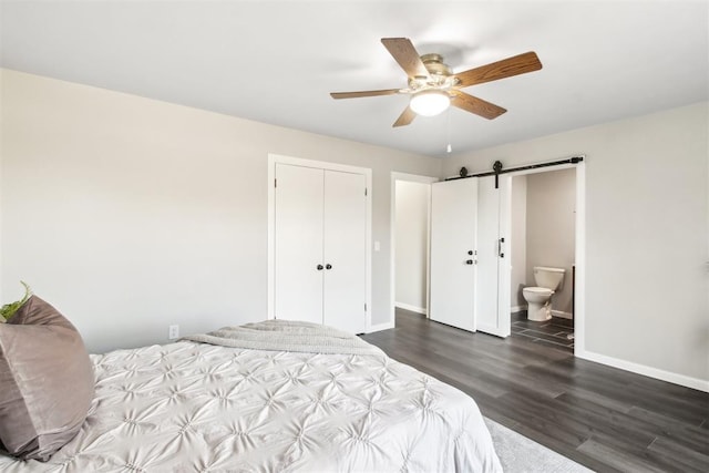 bedroom with a barn door, baseboards, a ceiling fan, dark wood-style flooring, and a closet