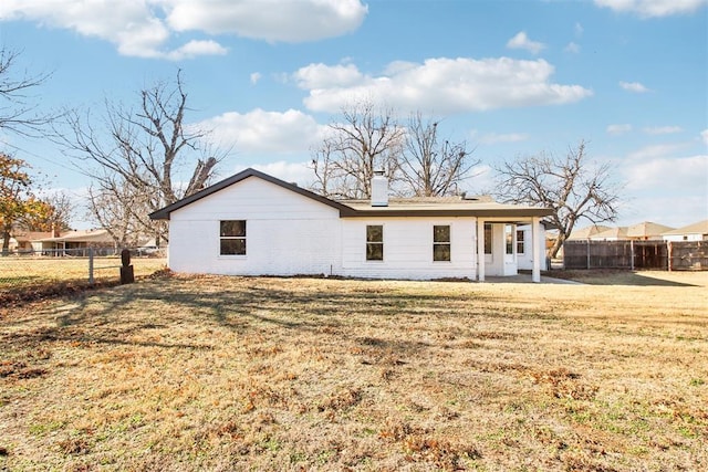 rear view of house with a chimney, fence, and a yard