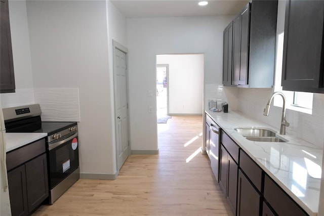 kitchen with light stone countertops, stainless steel appliances, tasteful backsplash, sink, and light wood-type flooring