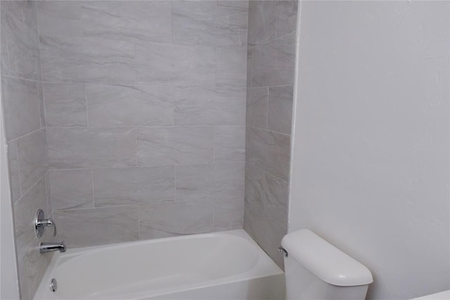 bathroom with toilet and tiled shower / bath