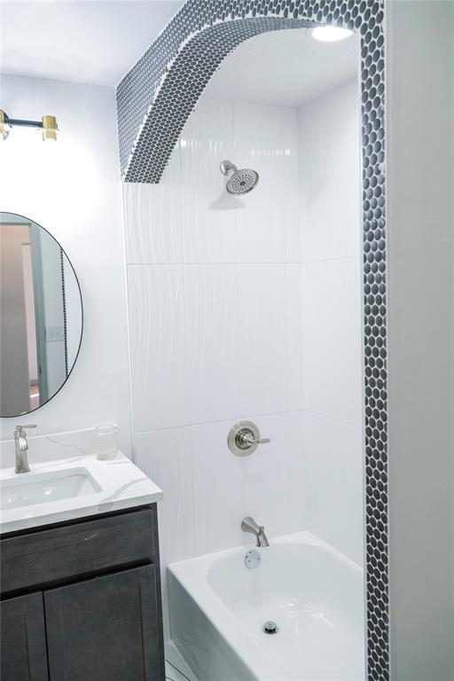 bathroom featuring vanity and tiled shower / bath