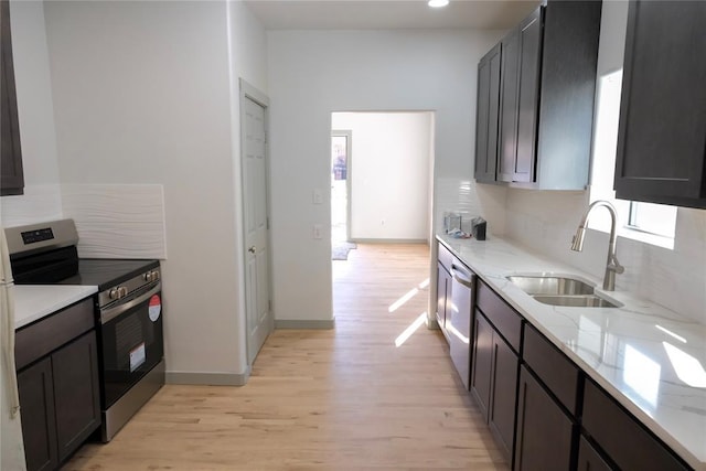 kitchen featuring tasteful backsplash, sink, light hardwood / wood-style flooring, light stone countertops, and stainless steel appliances