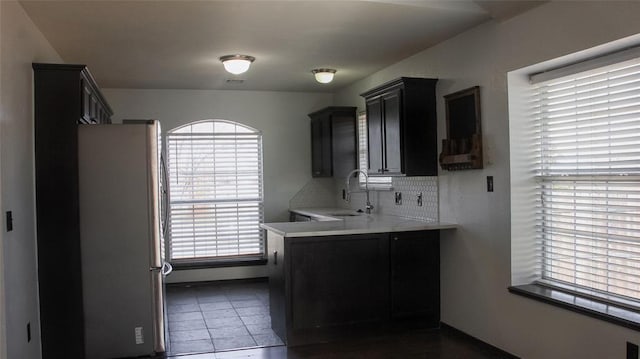 kitchen with decorative backsplash, stainless steel fridge, dark tile patterned floors, and sink